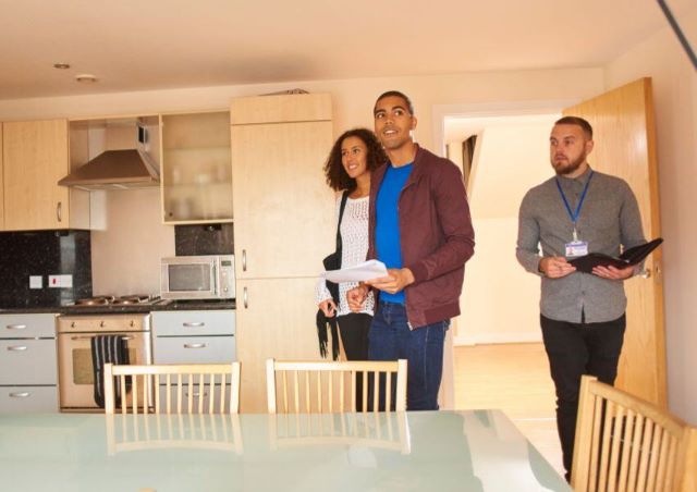 a couple of tenant taking a tour of a rental property with a property managers in the background